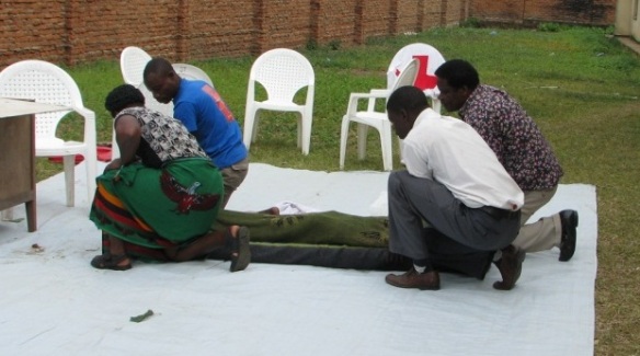 Fotobijschrift: De simulatie wat te doen bij een gekneusde ruggengraat wekte het meeste indruk: geen half werk in Malawi – het duurde twee dagen om de simulant uit zijn immobiliserings-positie te bevrijden. 